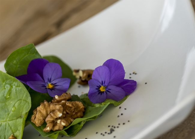 ensalada de espinacas con nueces, semillas de amapola y flores.