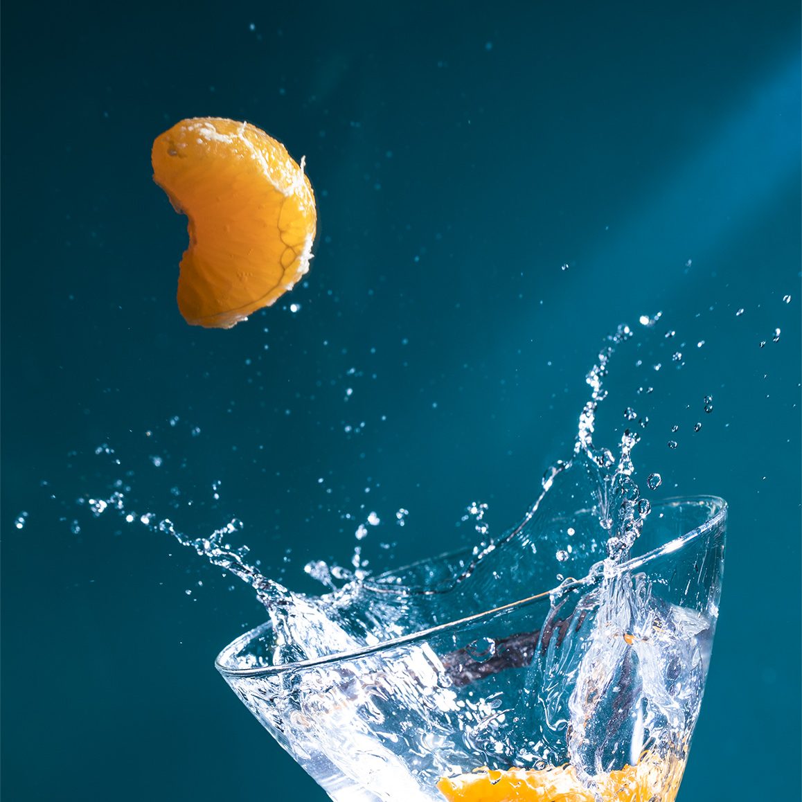 mandarina salpicando en una copa de coctel