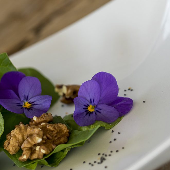 ensalada de espinacas con nueces, semillas de amapola y flores.